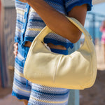 Cartera de cuero Cala Butter en amarillo pastel, llevada al hombro