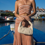Cartera de cuero Cala Cream en beige crema, combinada con un look a rayas